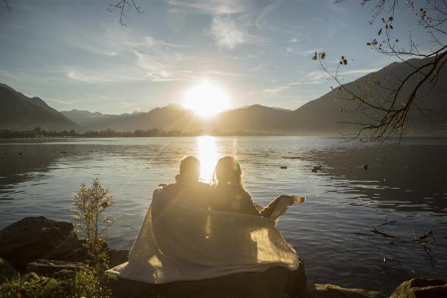 Couple by the lake watching sunrise