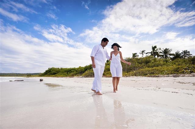 Happy engaged couple walking in a tropical beach