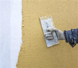 trowel with glove hand plastering a wall