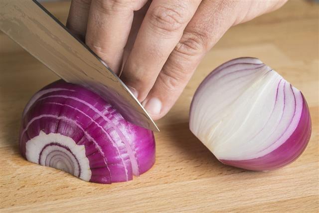 Chef chopping a red onion with a knife