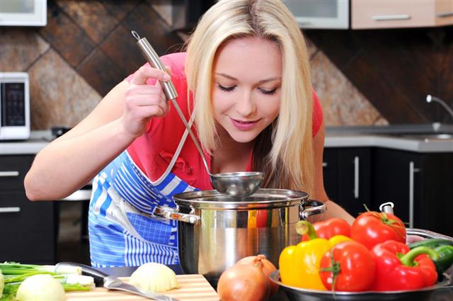 A blonde woman cooking vegetable soup