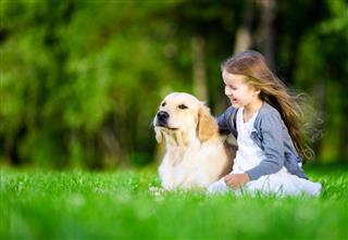 Little girl sitting on the grass with dog