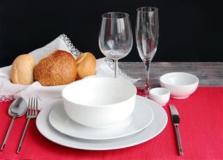 Table setting with bread rolls on a red napkin