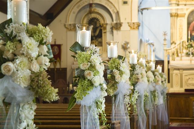 Row of cream wedding flowers with candles and white silk