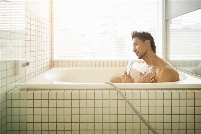 Asian man showering in Japanese bathtub