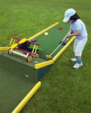 Young boy playing miniature golf