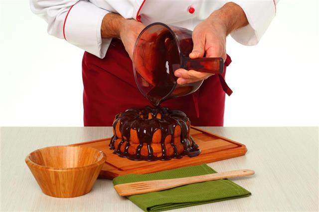 Pouring chocolate glaze onto cake