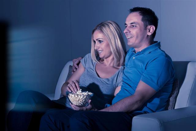 Couple Watching Television And Eating Popcorn At Home