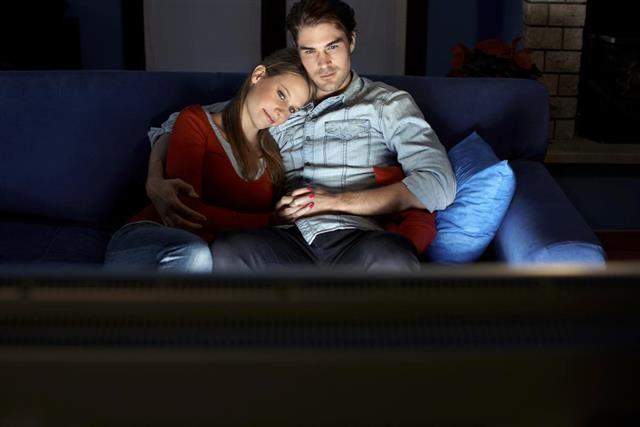 man and woman watching movie on TV