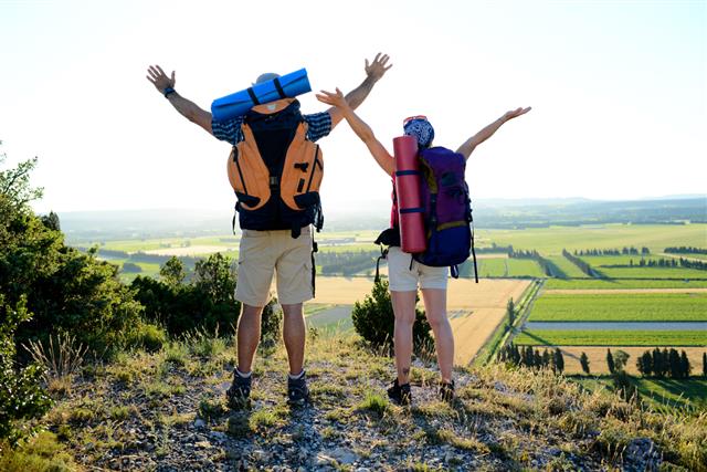 Young couple backpacker on mountain trek admiring beautiful sunset landscape