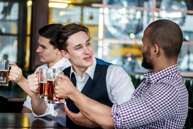 Four businessmen friends drink beer and spend time together