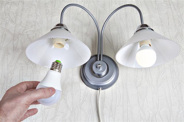 Replacing the bulbs in wall lights, hand holds LED lamp