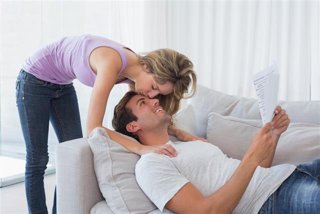 Woman kissing mans forehead while he reads document