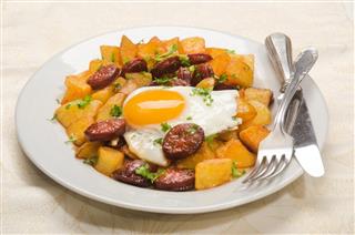 Spanish meal with sliced chorizo, roasted potato and fried egg