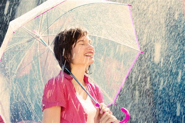 Woman in the rain with a pink and clear umbrella