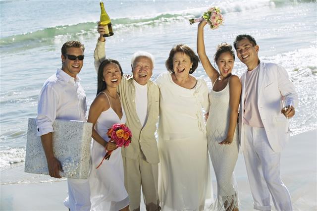 Newlywed Couples With Family Celebrating On Beach