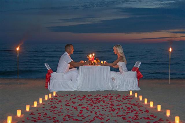Young couple share a romantic dinner with candles at beach