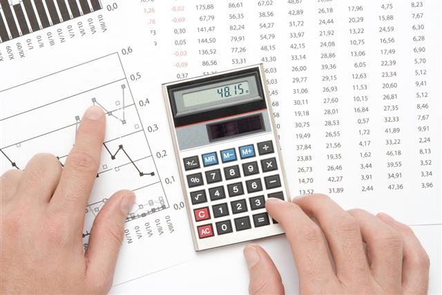 Calculator and finger pointing to graph in business analysis