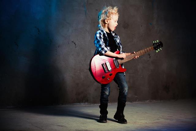 A young boy holding a rock guitar