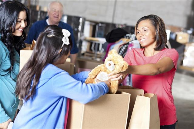 Woman giving teddy bear to needy family at donation center