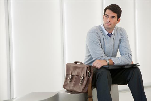 Businessman sitting in office lobby looking at camera