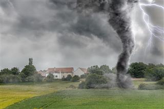 Black tornado funnel and lightning over field during thunderstorm