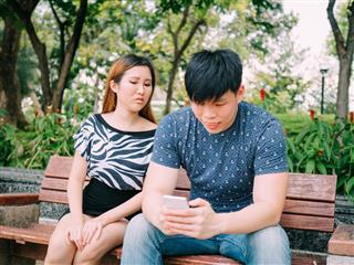 Jealous girlfriend peeking and spying her boyfriend mobile phone