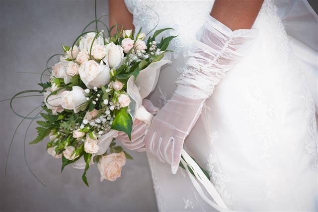 Bride wearing gloves holding bouquet