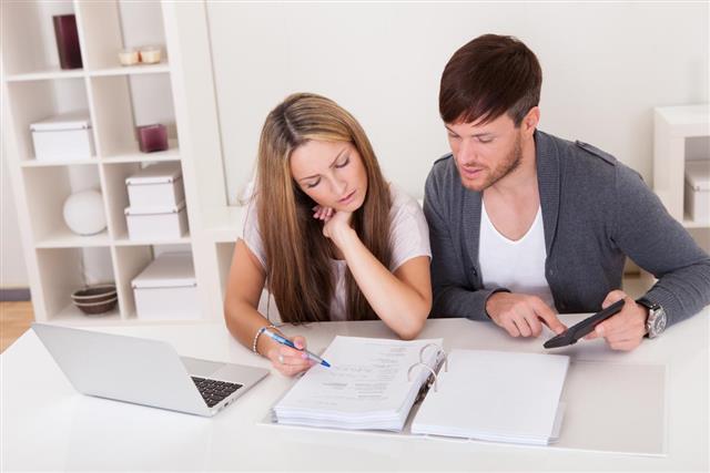 Serious couple looking over financial papers at desk at home