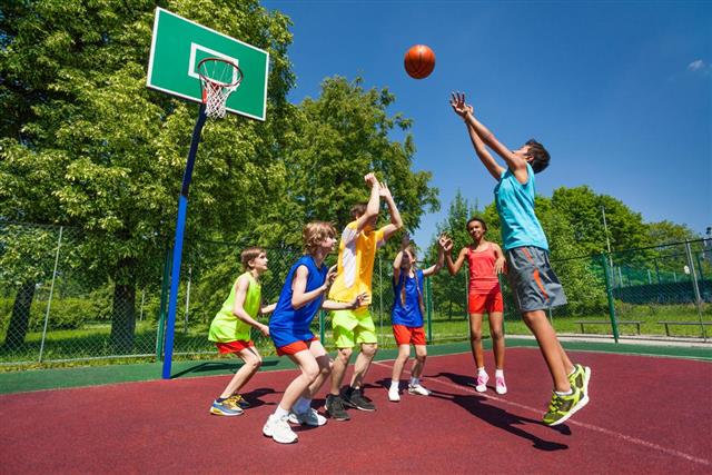 Teenagers playing basketball game together
