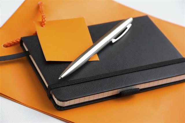 notepad with a pen on an orange bag