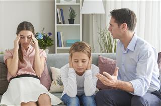 Boy covering ears with hands while her parents arguing