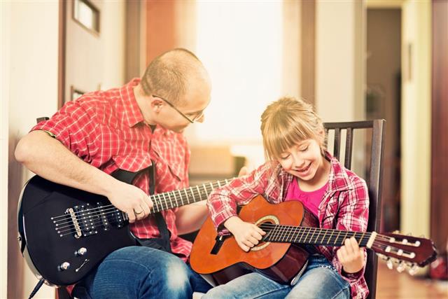 Father and daughter playing guitars together