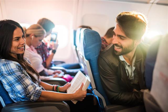 Young smiling man flirting with beautiful woman in airplane.
