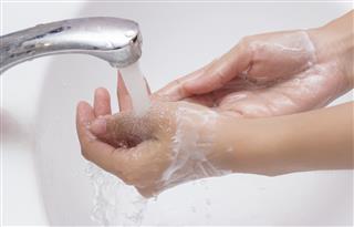 Woman washing hands with soap .