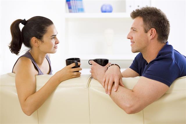 A man and woman drinking coffee on the couch