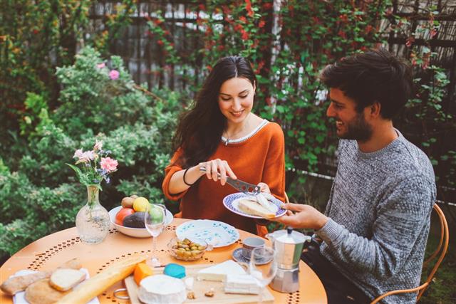 Young French couple having a brunch in the garden