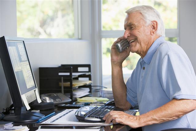 Man on telephone using computer smiling