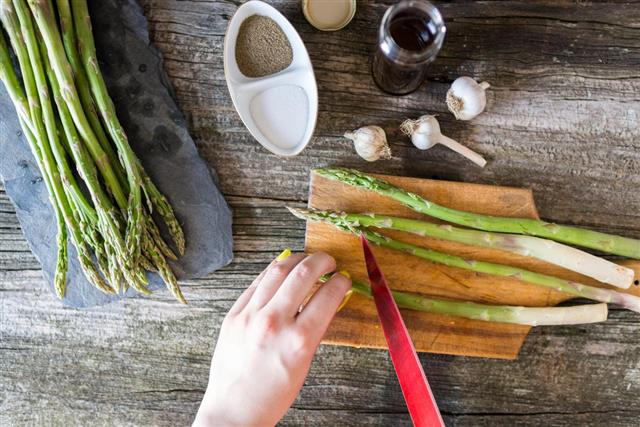 Woman's hands cutting fresh asparagus