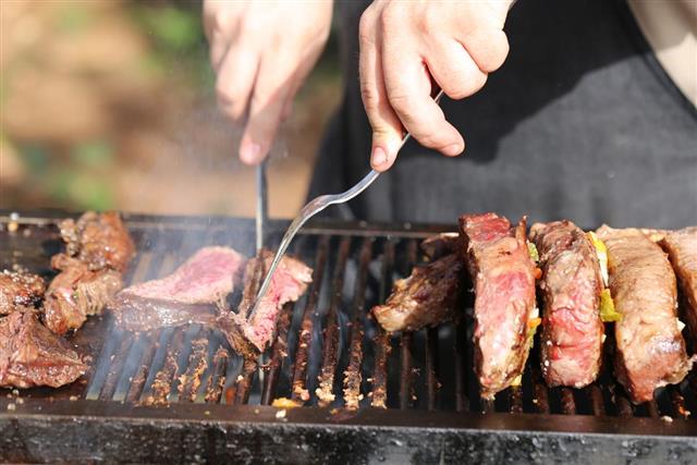 Hands Cutting Meat With Grill Tools