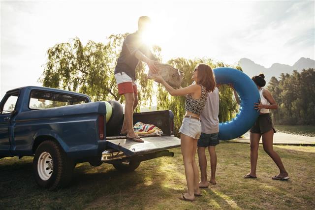Young friends unloading pickup truck on camping trip