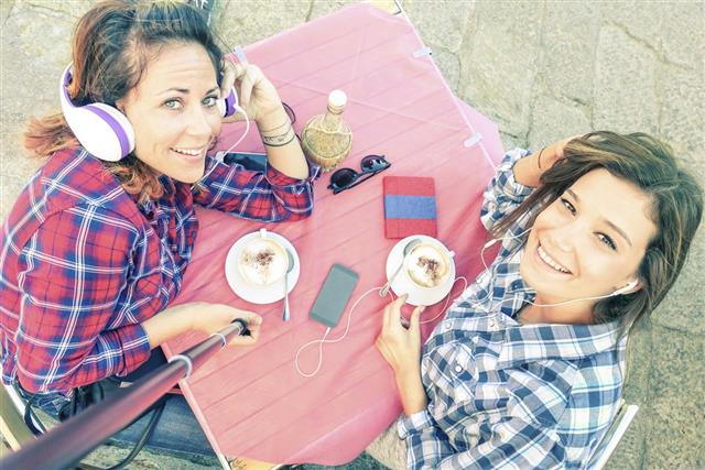 Top view of hipster girlfriends taking selfie drinking cappuccino