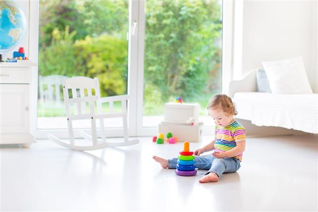 Cute toddler girl playing in white room with big window