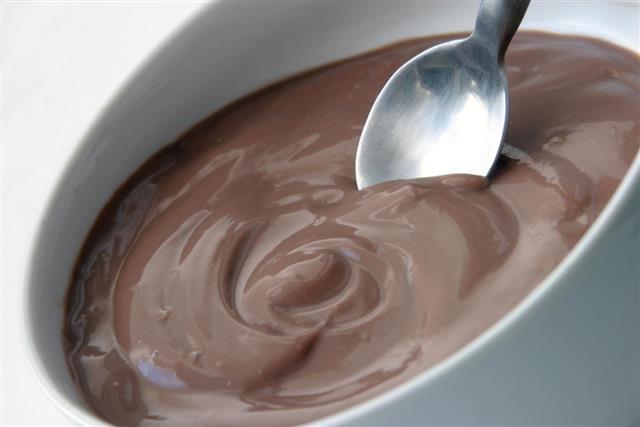 Spoon being dipped into bowl of chocolate mousse