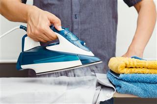 Man irons clothes on ironing board