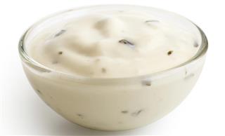 Small glass condiment bowl of white garlic and herb sauce.