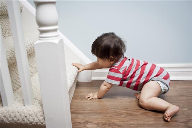 A baby boy crawling towards the stairs