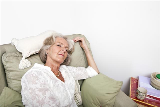 Tired senior woman sleeping on armchair at home