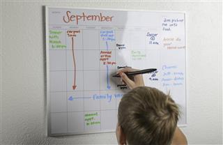 Boy drawing on daily schedule whiteboard