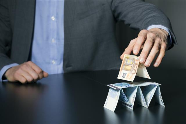Businessman building financial pyramid from euro money